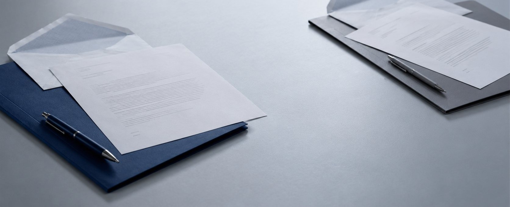 Two document folders positioned at a distance across a table, representing two positions in a dispute not yet aligned.